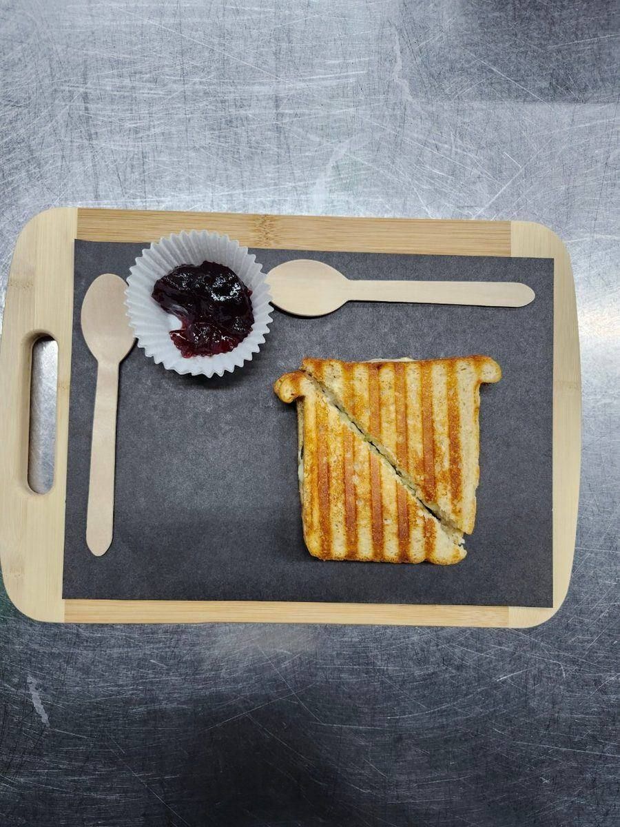 The BEST Grilled Cheese on a slate serving board with a side cup of JoJo's Aprihot compote