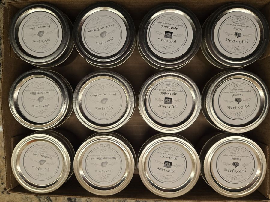 A box of assorted JoJo's Jams pots — ApriHot, PeachGi, Strawberry Rhubarb and Strawberry Bliss