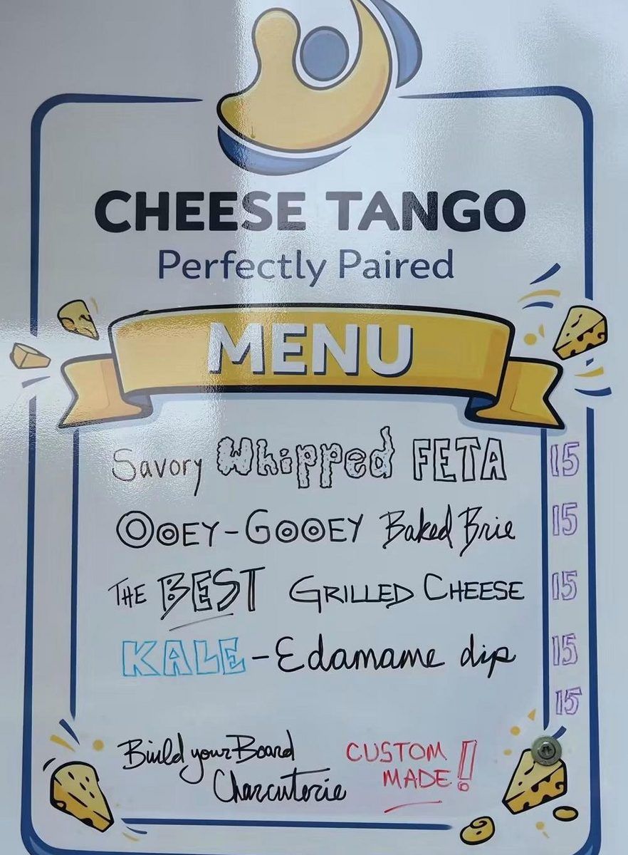 The Cheese Tango menu board on the trailer: Savory Whipped Feta, Ooey-Gooey Baked Brie, The BEST Grilled Cheese, Kale-Edamame Dip, and Build your Board Charcuterie