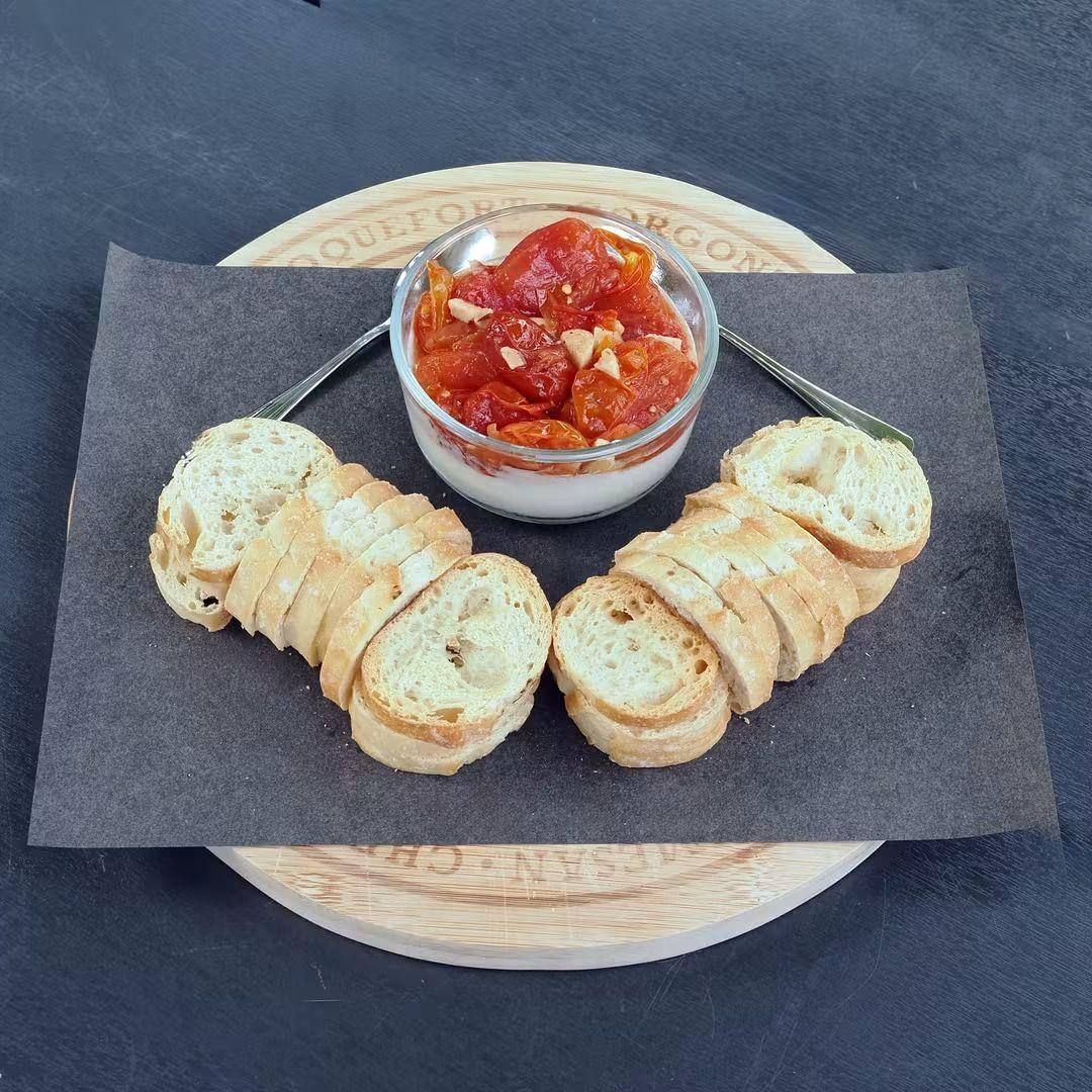 A savoury red dip served over a creamy base with sliced crostini